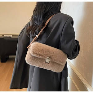 Detail view of a beige faux fur shoulder bag with silver turn-lock and leather strap