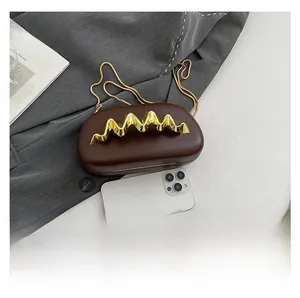Details der dunkelbraunen Hartschalen-Abendtasche mit goldenem Wellengriff und Kette