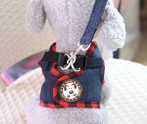 Detail of denim dog harness with red plaid trim, cartoon shine patch and metal clip