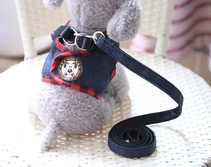 Close-up of blue denim dog harness with red plaid trim and shine leather badge