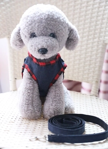 Detail of denim dog harness with red plaid trim on a grey plush model toy