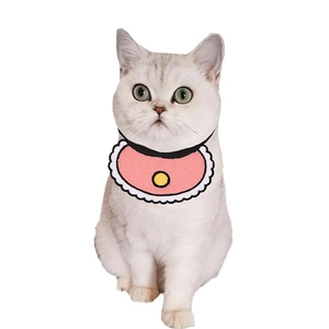 Close-up of pink pet bib with white lace trim and yellow pattern on white cat