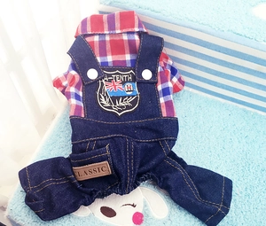 Detail of plaid pet shirt and denim overalls with decorative badges and leather label