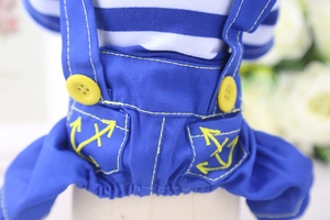 Detail of pet overalls with anchor embroidery and yellow buttons on striped fabric