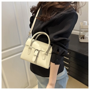 Chic cream white crossbody bag with silver buckle worn by model in a modern room