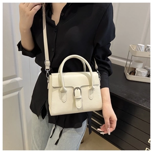 Chic off-white leather handbag with adjustable strap shown in a modern lifestyle setting