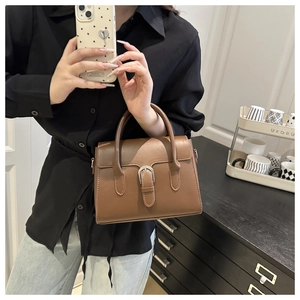 Brown leather handbag detail featuring silver horseshoe buckle and trapezoid shape