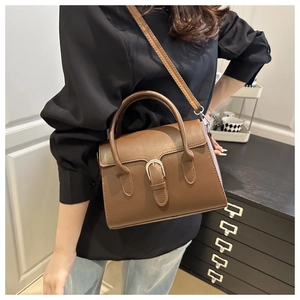 Brown matte leather crossbody bag with vintage metal buckle shown on a model