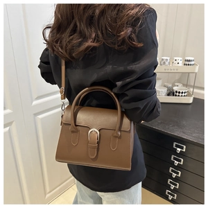 Rear view of model wearing a vintage brown crossbody bag with silver buckle details