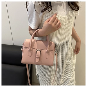 Detail view of pink leather crossbody bag with silver buckle and adjustable shoulder strap