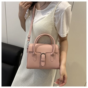 Detailed shot of pink leather crossbody bag with horsebit buckle worn by model