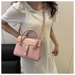 Detail of pink leather handbag with silver buckle worn as a stylish crossbody bag