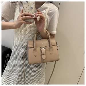 Close-up of apricot leather handbag with buckle detail and adjustable shoulder strap