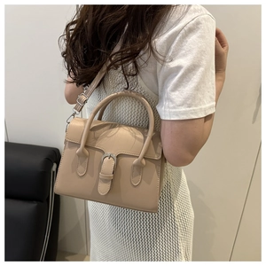 Close-up of beige trapezoid handbag with iconic D-shaped hardware and dual top handles