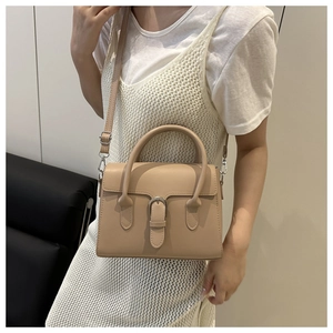 Beige crossbody bag with belt buckle detail shown on white knitted dress