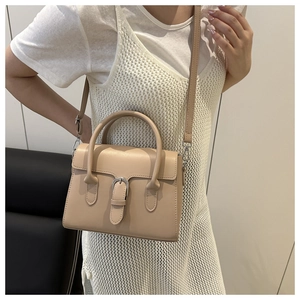Detail view of beige crossbody bag with silver buckle and adjustable shoulder strap