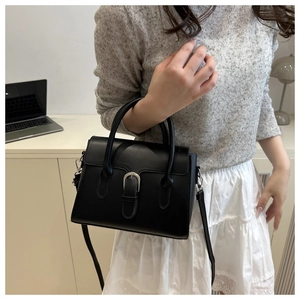 Classic black leather crossbody bag with silver buckle shown in a lifestyle setting
