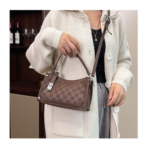 Detail of dark brown checkered crossbody bag held by model in elegant home setting