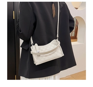 Detail of white embossed checkerboard crossbody bag showing rivet accents and fine texture