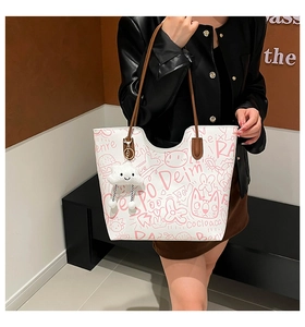 Detail of white tote bag with pink graffiti patterns and a plush cloud charm accessory