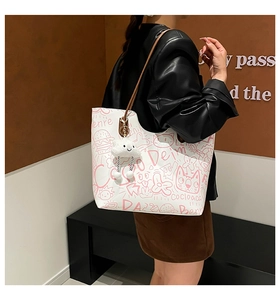 Close-up of white tote bag featuring pink graffiti art and a plush cloud charm