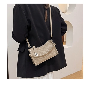 Side view of model wearing a beige quilted crossbody bag with silver hardware and blazer
