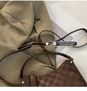Macro shot of dark brown checkered pattern shoulder strap with metal buckle and bag detail
