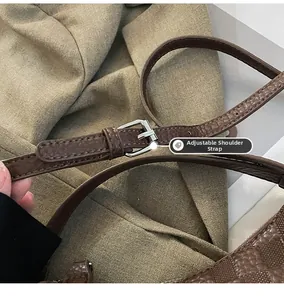 Detail of adjustable dark brown leather shoulder strap with embossed texture and buckle