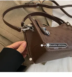 Detail of dark brown pebble leather handbag with silver buckles and fine stitching work
