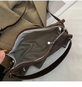 Interior detail of large brown leather Boston bag with grey herringbone lining and zip pocket