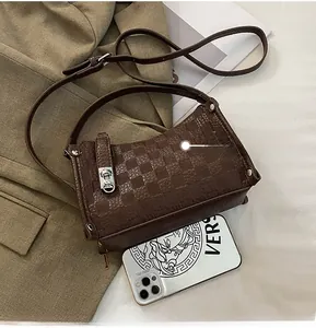 Detail view of brown quilted crossbody bag with silver clasp and adjustable shoulder strap