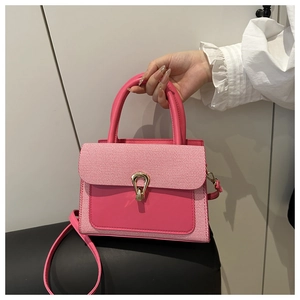 Detail of rose pink handbag featuring leather and textured weave paneling with gold buckle