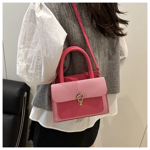 Detail of pink patchwork crossbody bag with gold horseshoe buckle and striped fabric texture