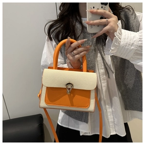 Mirror selfie showing orange leather and beige woven patchwork handbag with gold U-buckle