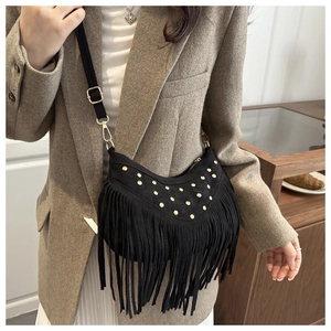Borsa a mezzaluna in camoscio nero con borchie dorate e frange indossata da modella