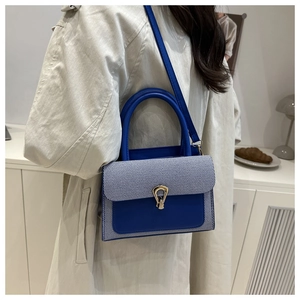 Detail of blue patchwork handbag with golden horseshoe clasp shown in a lifestyle setting