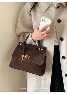 Close-up of retro dark brown suede handbag with golden hardware and key charm detail