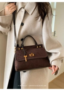 Close-up of matte suede handbag with vintage gold square buckle and key pendant