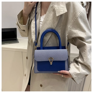 Blue patchwork crossbody bag featuring a golden buckle and stylish textured fabric flap