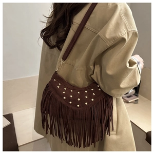 Brown suede fringed bag with gold studs and tassel detail shown on a model