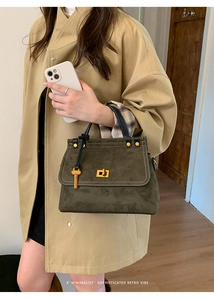Close-up of retro dark green suede handbag with golden twist lock and white stitching