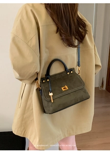 Detail of dark green vintage tote bag with gold twist lock and key charm on beige trench coat