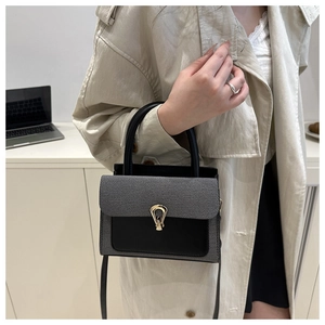 Close-up of dual-material gray and black crossbody bag with gold teardrop buckle