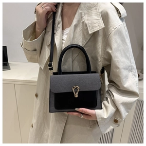 Detail of luxury two-tone handbag with golden horseshoe buckle and textured fabric finish