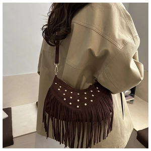 Detail of dark brown suede crescent bag featuring golden rivets and long fringe tassels
