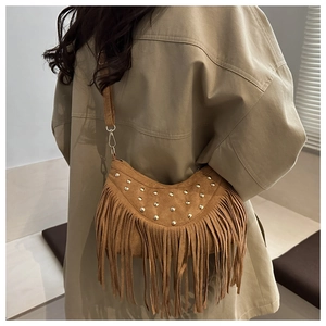 Dettaglio di una borsa a mezzaluna in camoscio marrone con borchie e lunghe frange