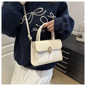 Detail of cream crossbody bag featuring woven texture flap and gold metallic hardware
