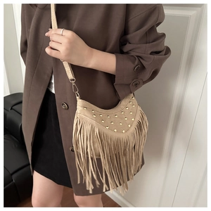 Dettaglio borsa a tracolla scamosciata beige con borchie dorate e lunghe frange