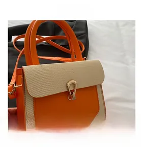 Close-up of contrast color handbag featuring orange leather and woven texture with gold lock