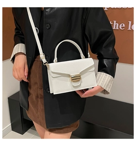Détail du sac blanc en cuir texturé avec une grande boucle en métal doré effet miroir